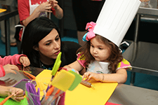 Girl cutting food in the Flo & Hy Siegel Pan to Plate Culinary Institute